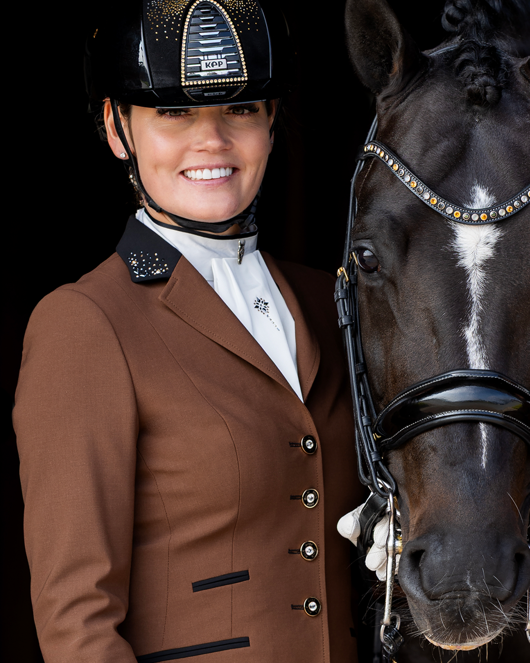 Close-up of a model next to a horse wearing JuulC' Women's Competition Jacket in Golden Espresso.