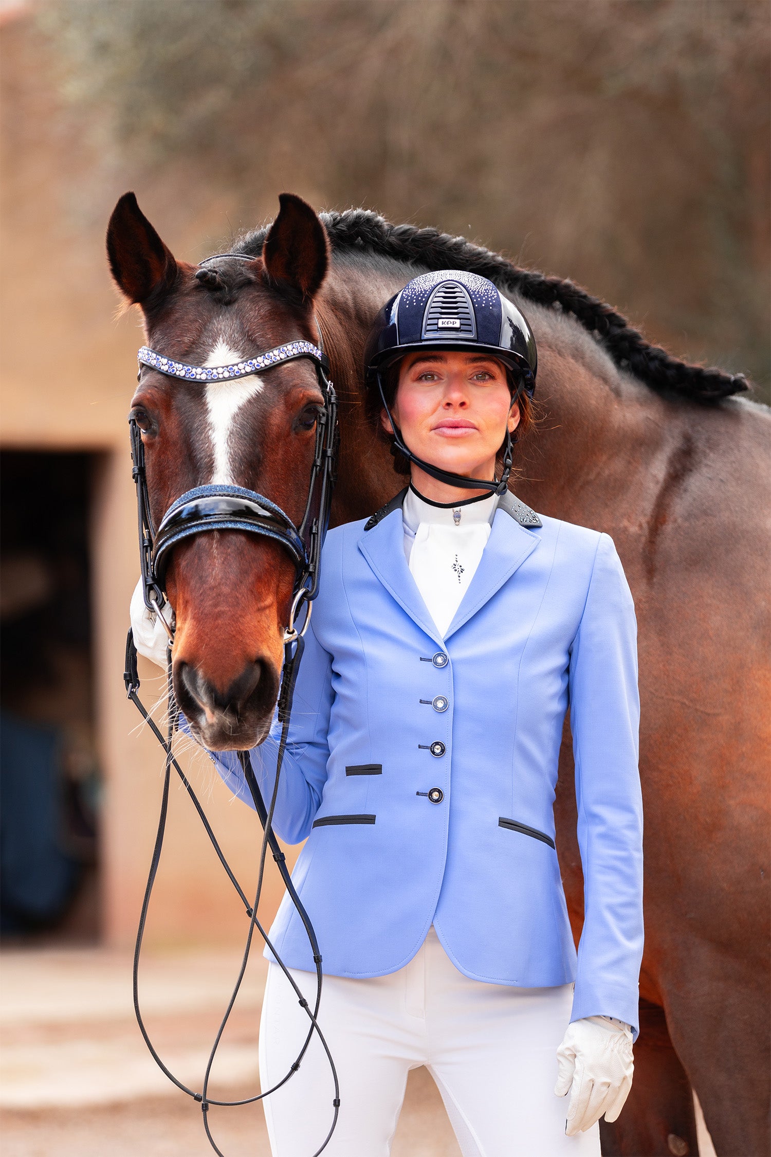 Model next to horse wearing JuulC' Lavender Blue Women's Show Coat, with light blue base and anthracite details