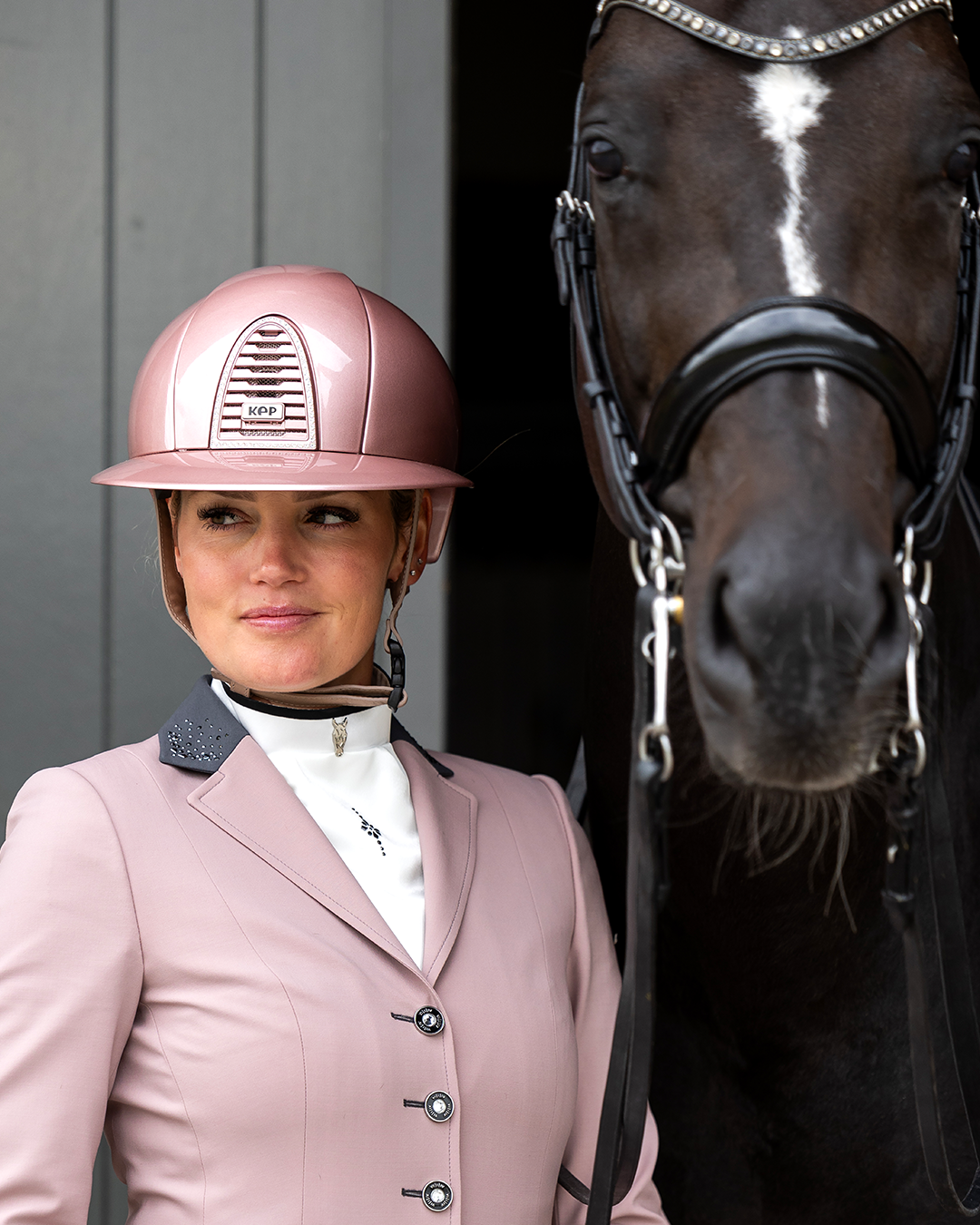 Model next to horse wearing JuulC' Powder Pink Women's Show Coat made from sport-tech merino wool 